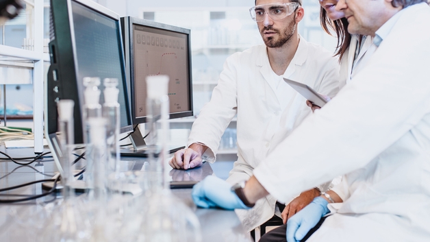 Personal científico trabajando en el laboratorio y mirando a una pantalla de ordenador